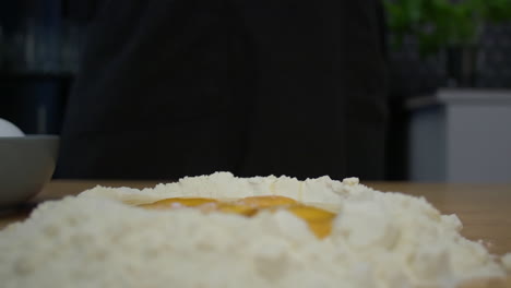 Adding-a-pinch-of-salt-into-flour-and-egg-yolks-mound---Eye-level-close-up-shot