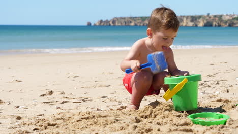 Cute-Little-Boy-Playing-with-Bucket-and-Shovel-in-Sand-at-Sunny-Beach