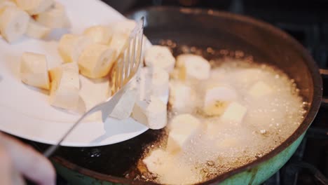 Sliced-banana-is-poured-into-a-pan-with-boiling-oil-to-be-fried