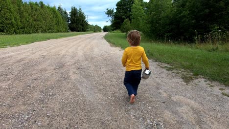 Cute-Caucasian-Male-Toddler-Walking-Barefoot-On-A-Dirt-Road---Farm-Adventure-During-Cherry-Festival-In-Traverse-City,-Leelanau-County,-Michigan,-USA---Tracking-Shot