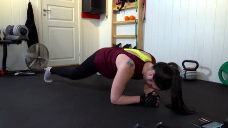 Mixed-race-young-woman-doing-forearm-plank-jacks-in-home-gym-during-quarantine