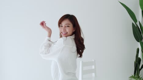 Lovely-Asian-woman-happy-dancing-with-glad-emotion-and-smiling-in-the-white-room