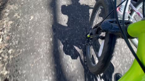 Biking-though-path-in-forest-on-bike-trail-with-closeup-of-front-bike-tire-and-passing-path---mountain-bike