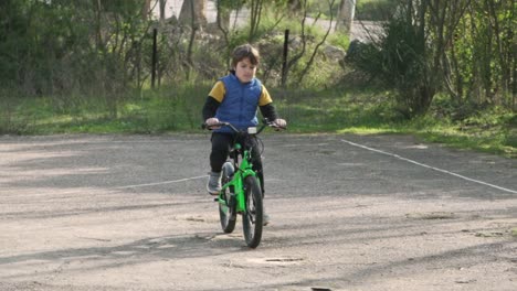 Slow-motion-of-greek-caucasian-boy,-riding-his-bicycle-on-cement-ground,-passing-out-of-the-screen