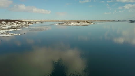 Filmische-Luftaufnahme-über-Dem-Olfusa-fluss-In-Der-Nähe-Von-Selfoss-Island-Mit-Himmel,-Der-Sich-Auf-Dem-Wasser-Spiegelt