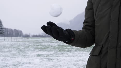 Slow-motion-shot-of-person-with-winter-gloves-throwing-snowball-up,-ready-for-throw