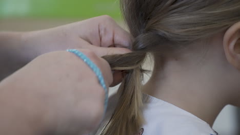 Mother-braiding-a-little-girl's-hair,-close-up