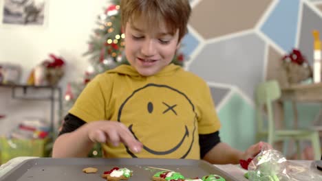 Caucasian-kid-tasting-sugar-icing,-preparing-Christmas-homemade-gingerbread-cookies,christmas-tree-on-the-blurry-background-4k