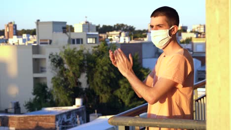 Young-man-applauding-health-workers-from-the-balcony-at-sunset
