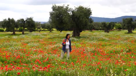 Frau-Beim-Blumenpflücken-In-Einem-Mohnfeld-Mit-Alten-Olivenbäumen-Im-Hintergrund-In-Italien