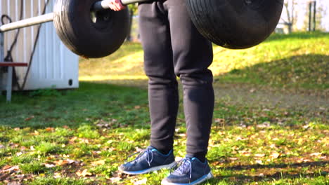 Guy-doing-deadlift-with-a-metal-bar-and-tires-in-a-park,autumn,Czechia