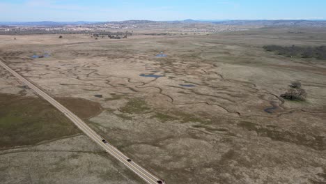 A-road-with-cars-drive-through-a-field-covered-in-protected-Vernal-Pools-in-the-Central-valley-of-California-seen-in-an-ep-of-California's-Gold
