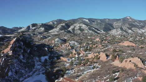 Aerial-fly-over-red-rock-valley-with-snow-on-sunny-day
