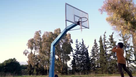 Kaukasischer-Junge-Dribbelt-Und-Schießt-Einen-Basketball-Im-Freien-Auf-Einer-Straße-Basketballkorb-In-Der-Nähe-Eines-Waldes-In-Parnitha,-Athen,-Griechenland