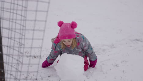 Cute-little-girl-takes-a-bite-out-of-a-snowball,-slow-motion