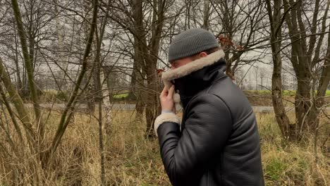 Slow-motion-track-shot-of-young-fashionable-man-with-hat-and-leather-jacket-walking-outdoors-in-nature