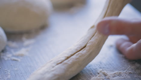 Close-up-of-white-male-hands-handling-dough-on-wooden-table