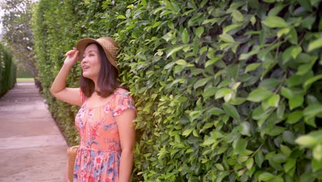 Beautiful-Asian-woman-on-vacation-looking-at-camera-near-green-wall