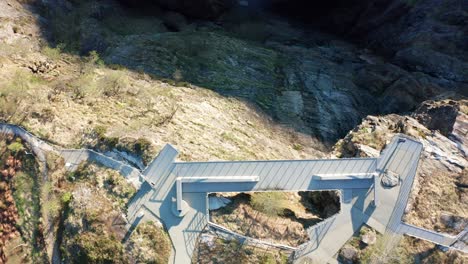 Spectacular-walkway-above-viewpoint-Vøringsfossen-waterfall-and-deep-canyon-at-Hardangervidda-Norway---Top-down-aerial-view-of-person-on-edge-of-walkway