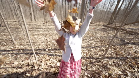 Happy-little-girl-throwing-a-pile-of-leaves-into-the-air,-slow-motion