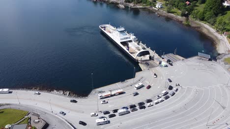 Car-and-passenger-ferry-Mf-Oppdeal-loading-and-discharging-cars-to-road-E39-at-Lavik-harbour---Static-aerial-showing-ferry-with-port-and-ferry-queue---Norway