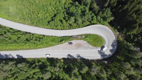180-degree-curve-at-winding-road-E39-through-deep-forest-in-Førde-Norway---Static-top-down-birdseye-aerial-view-with-passing-cars