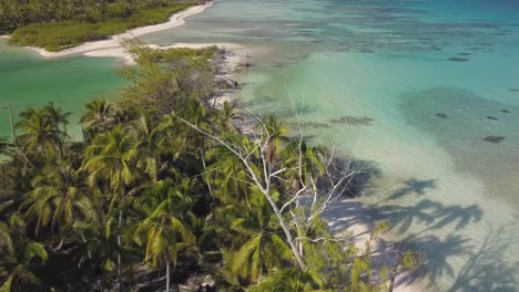 Luftdrohnenaufnahme-Eines-Tropischen-Strandes-Und-Einer-Lagune-Mit-Langen-Schatten-Von-Kokospalmen,-Die-Rückwärts-Fliegen