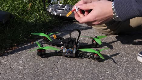 Close-up,-caucasian-drone-pilot-mounts-battery-on-a-fpv-racing-drone