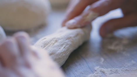 Close-up-of-young-white-male-hands-kneading-dough-on-wooden-table