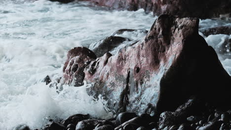 Slow-motion-shot-of-strong-waves-crashing-against-red-and-black-colored-basalt-rocks-at-Hawaiian-coast