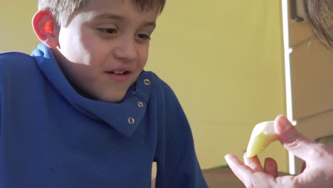 Cute-caucasian-boy,-eating-apple-at-balcony-on-a-sunny-bright-day-120fps-close-up