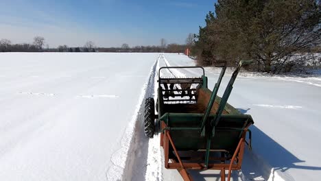 Farm-Machinery-Manure-Spreader-Running-Across-A-Snowy-Field-During-Sunny-Winter-Day-In-Southeast-Michigan
