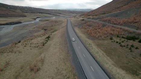 Luftaufnahme-Eines-Autos,-Das-Auf-Einer-Leeren-Isländischen-Autobahn-Durch-Das-Tal-Fährt