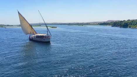 Aerial-drone-shot-of-a-sailing-ship-navigating-through-Nile-river-as-a-tourist-cruise