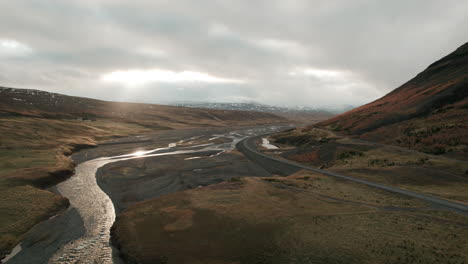 Aerial-parallax-over-Iceland-river-valley,-bathed-in-dramatic-storm-light