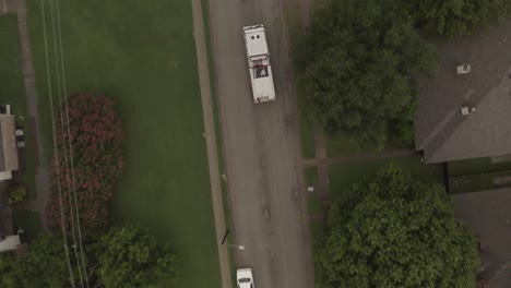 From-above,-a-fire-truck-travel-on-a-neighborhood-street-passing-cars-pulled-over-for-it's-safe-passage.