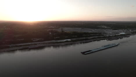 Tugboat-pushing-barges-up-Mississippi-River-at-sunset