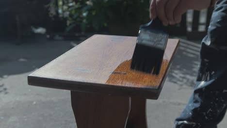 Brushing-varnish-on-teak-timber-stool-outdoor-4K