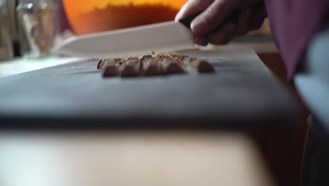 Close-up-on-woman's-hands-chopping-chocolate-,-preparing-homemade-energy-bars