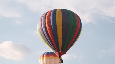 Slow-tracking-shot-of-colorful-hot-air-balloons-moving-past-puffy-clouds
