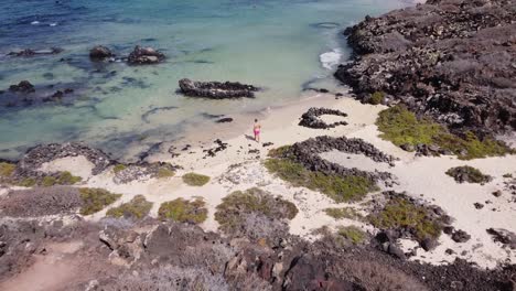 Aerial-drone-footage-of-a-guy-chilling-in-a-nice-beach-with-turquoise-waters-in-Lanzarote,-Canary-islands