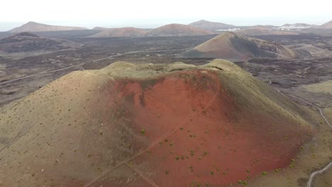 Aerial-drone-footage-of-a-huge-red-volcano-and-a-solitary-road-in-Canary-islands,-Spain