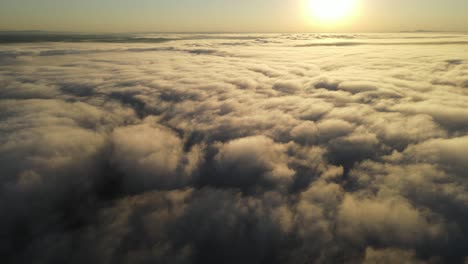 Flying-over-a-blanket-of-clouds-at-sunrise-as-if-looking-out-the-window-of-an-airplane