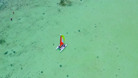 Catamaran-with-colorful-sail-navigating-on-turquoise-Caribbean-sea-water