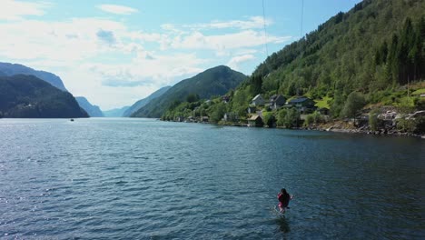 Frau,-Die-Spektakuläre-Hohe-Schaukel-Mit-Dem-Norwegischen-Fjord-Veafjord-Im-Hintergrund-Reitet---Luftbild-Zeigt-Eine-Frau,-Die-Ihre-Füße-In-Die-Meeresoberfläche-Baumelt,-Umgeben-Von-Einer-Atemberaubenden-Landschaft---Norwegen