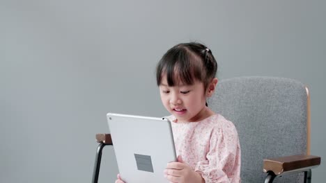 Asiatisches-Mädchen,-Das-Zu-Hause-E-learning-Per-Videoanruf-Online-Lernt,-Indem-Es-Ein-Tablet-Verwendet-Und-Mit-Lehrern-Und-Klassenkameraden-Als-Neue-Normale-Und-Soziale-Distanzierung-Spricht