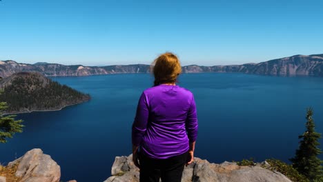 Red-head-with-a-purple-shirt-stands-on-the-edge-of-Crater-Lake-National-Park