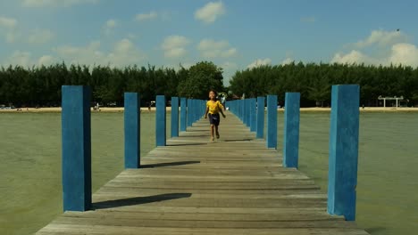 little-girl-running-on-the-beach-bridge-with-the-sun-coming-from-the-side-so-that-a-body-shadow-appears