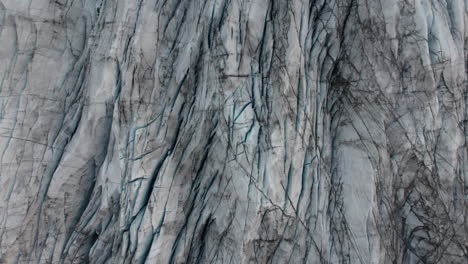 Aerial-rise-over-glacier-surface-covered-in-cracks-and-deep-crevasses,-Iceland