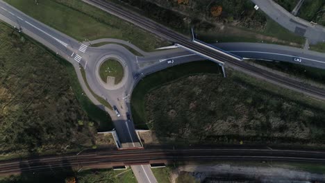 Traffic-circle-on-aflat-street-with-passing-cars-combined-with-railroad-tracks-recorded-from-above-from-a-drone